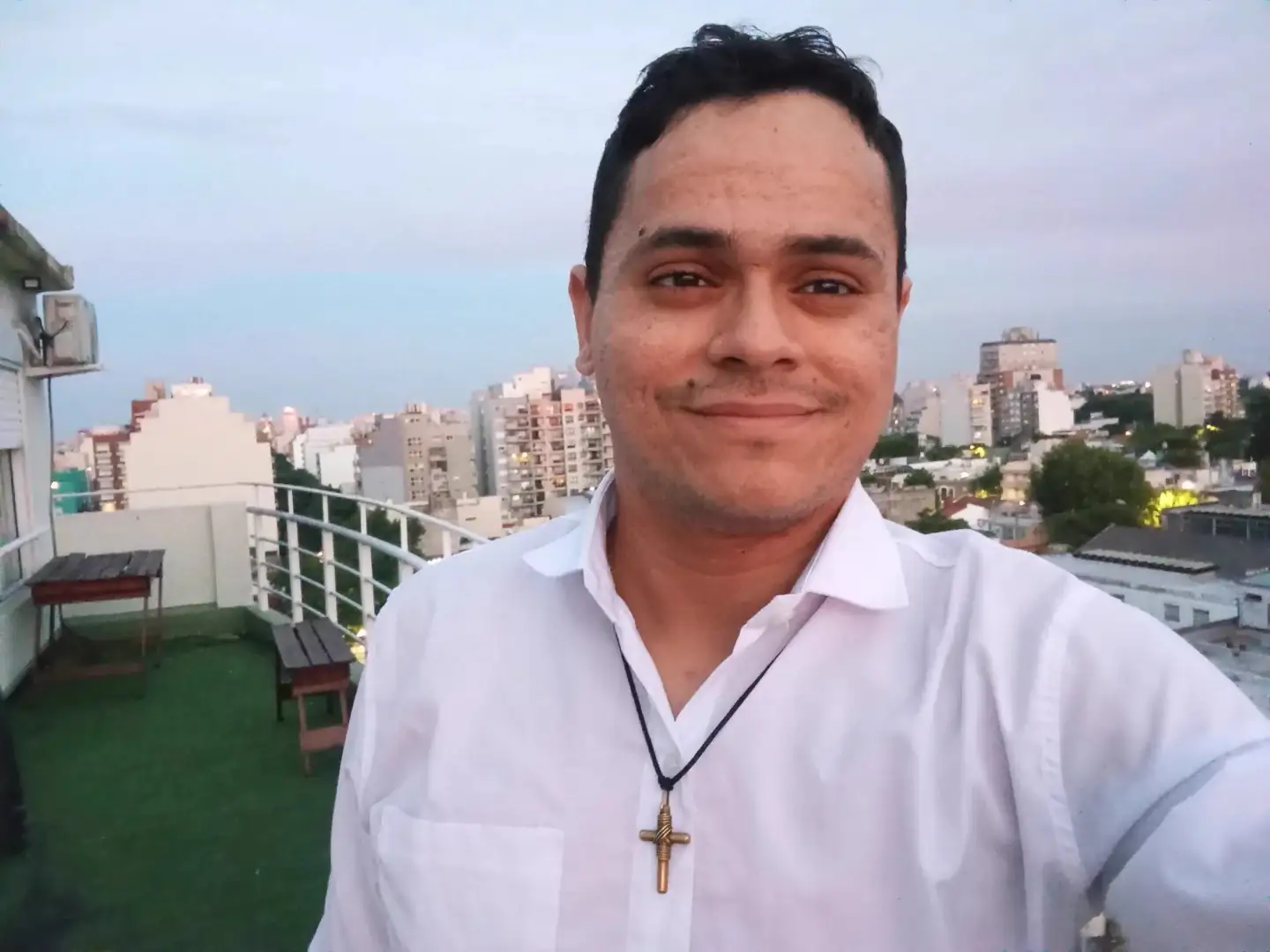 Sebastián smiling on a rooftop, with Buenos Aires behind him at dusk