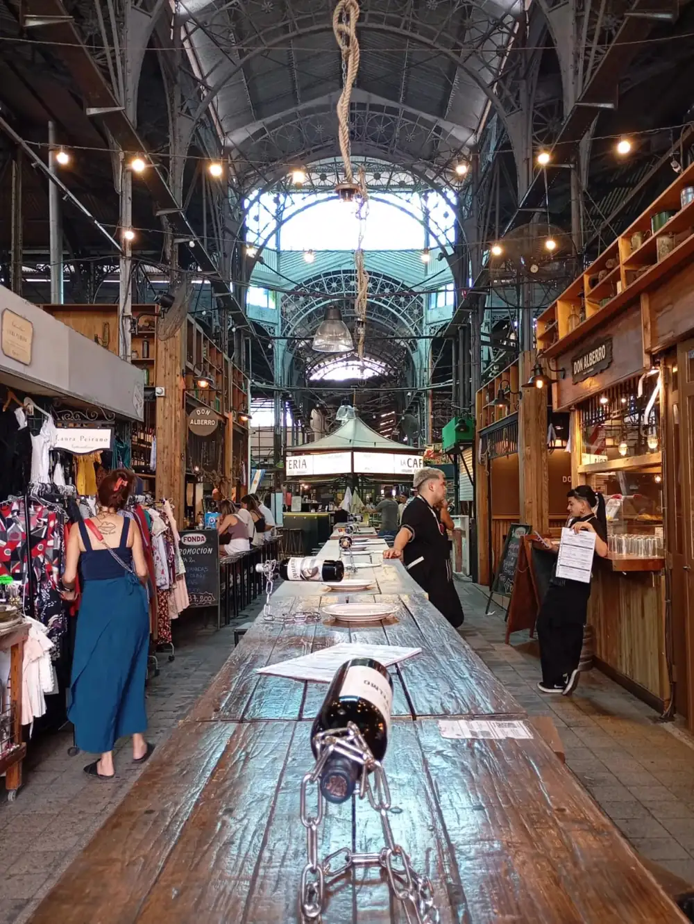 Inside Mercado de San Telmo, a long wooden table under the iron roof