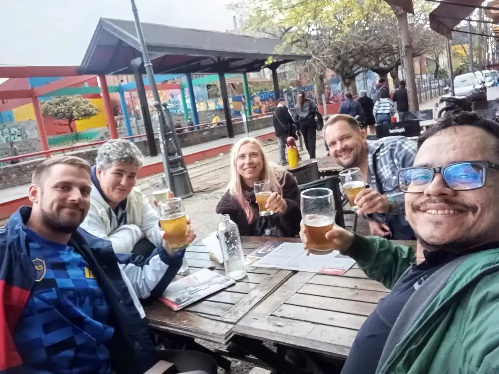 Sebastián and four guests raising glasses of beer at a table in La Boca