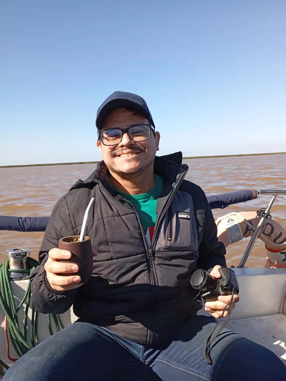 Sebastián on a boat on the river, holding a mate