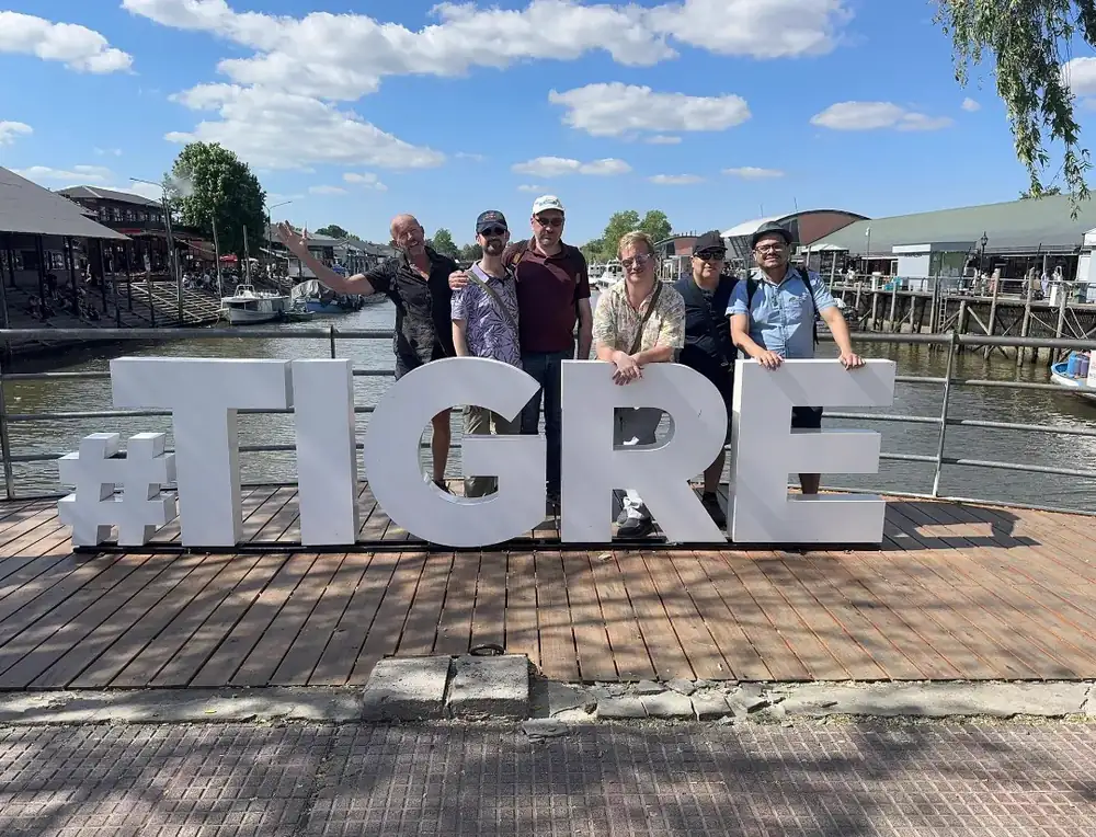 A tour group standing behind the big #TIGRE letters by the river