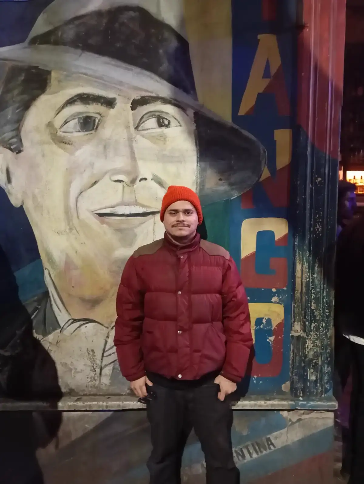 Sebastián in front of the Carlos Gardel mural at the tango bar El Boliche de Roberto
