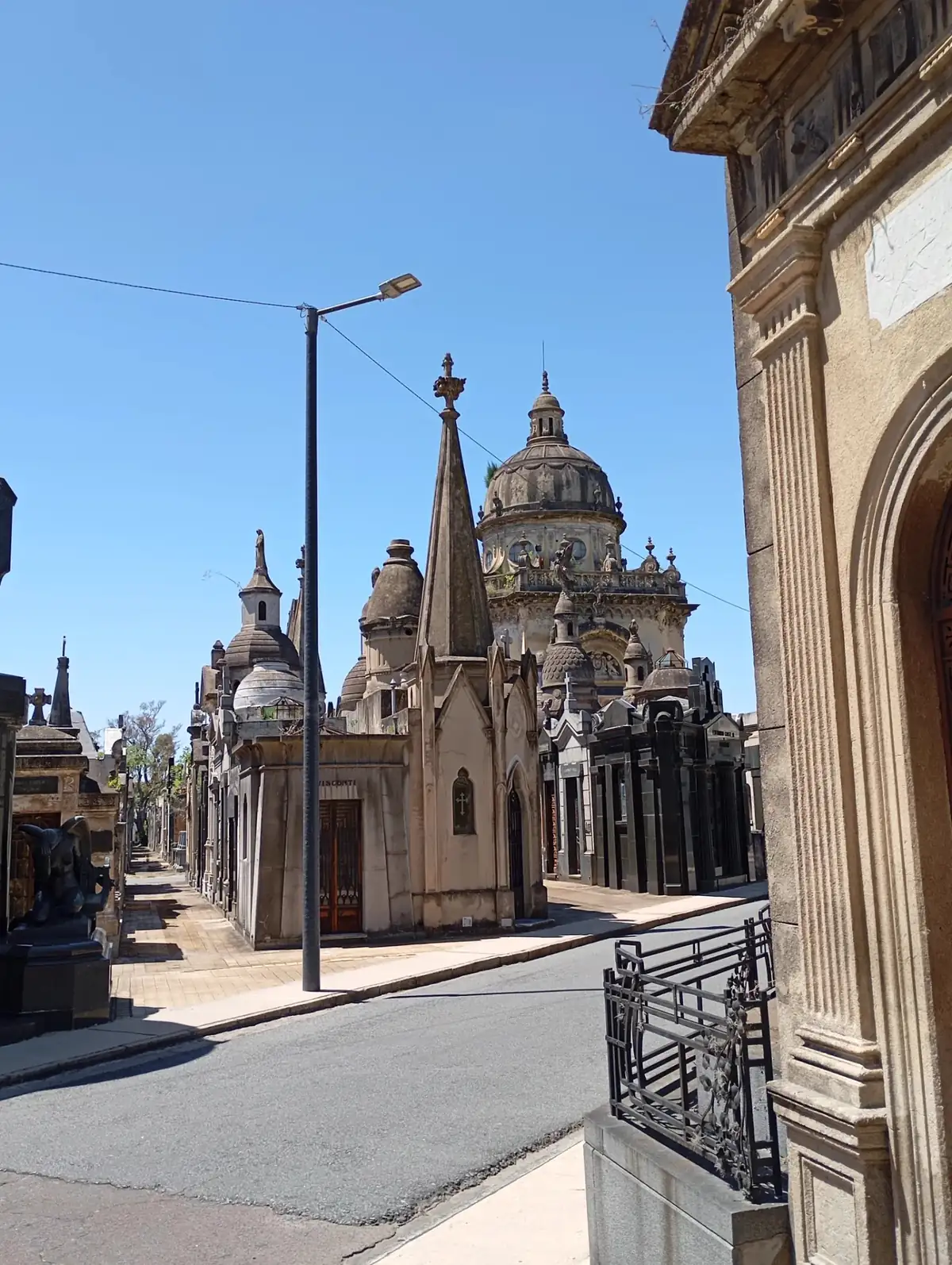 A street of domed mausoleums in Chacarita cemetery under a blue sky